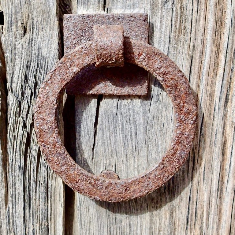 Eisenring an einer wettergegerbten Holztür. Als Symbol für ein Basis Sicherheitspaket in der Hausbetreuung, im Homeservice auf Mallorca 
