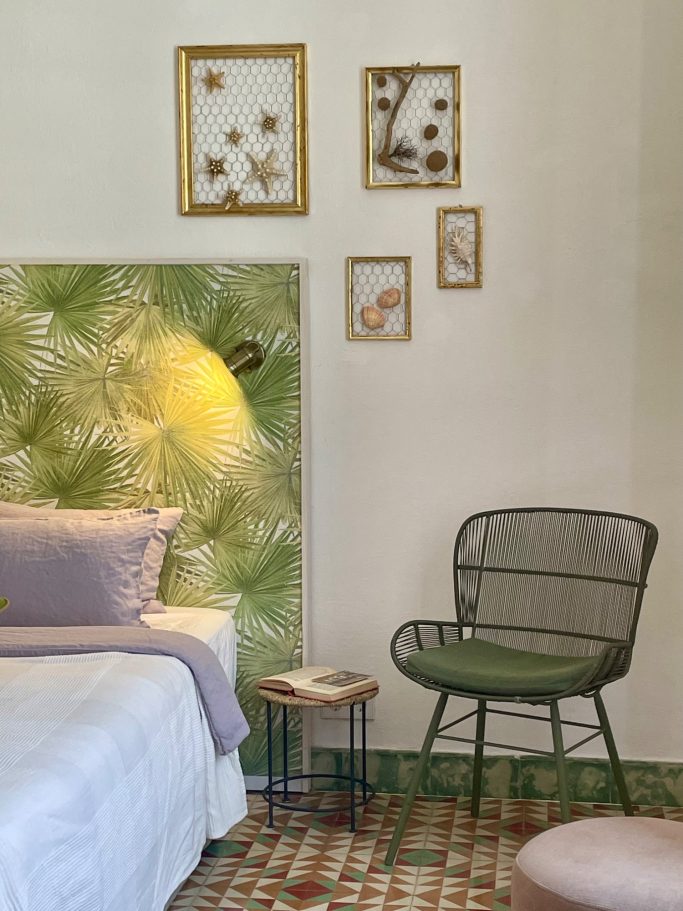 Ferienvermietung Gemütliches Schlafzimmer mit grüner Wand, Bildern, Bett und einem modernen Stuhl.