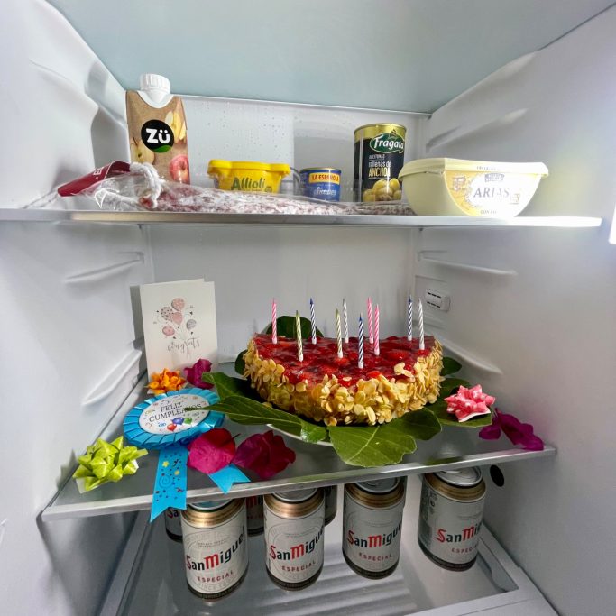 Gästebetreuung Kühlschrank mit einem Kuchen mit Kerzen, Dosen und verschiedenen Lebensmitteln.