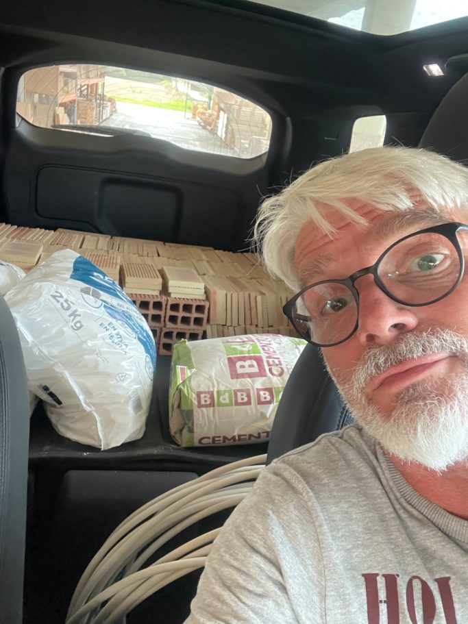 Baubegleitung / Renovierung Ein Mann mit Brille sitzt im Auto, im Hintergrund Einkaufstüten und Gegenstände sichtbar.