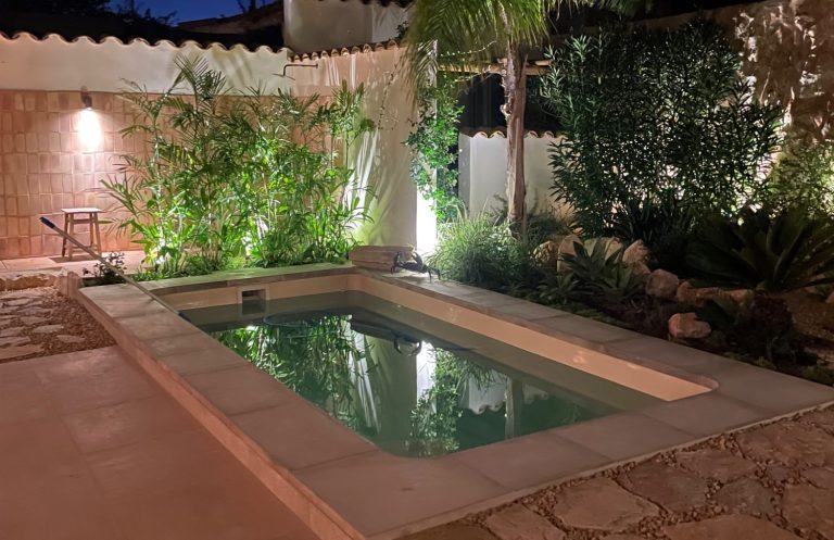 Kleiner, geheimer Gartenpool umgeben von Pflanzen und sanfter Beleuchtung. Poolpflege Mallorca