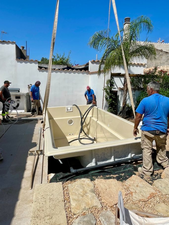 Einbau eines Pools Eine Gruppe von Personen hebt ein großes Schwimmbecken mit Kränen an.