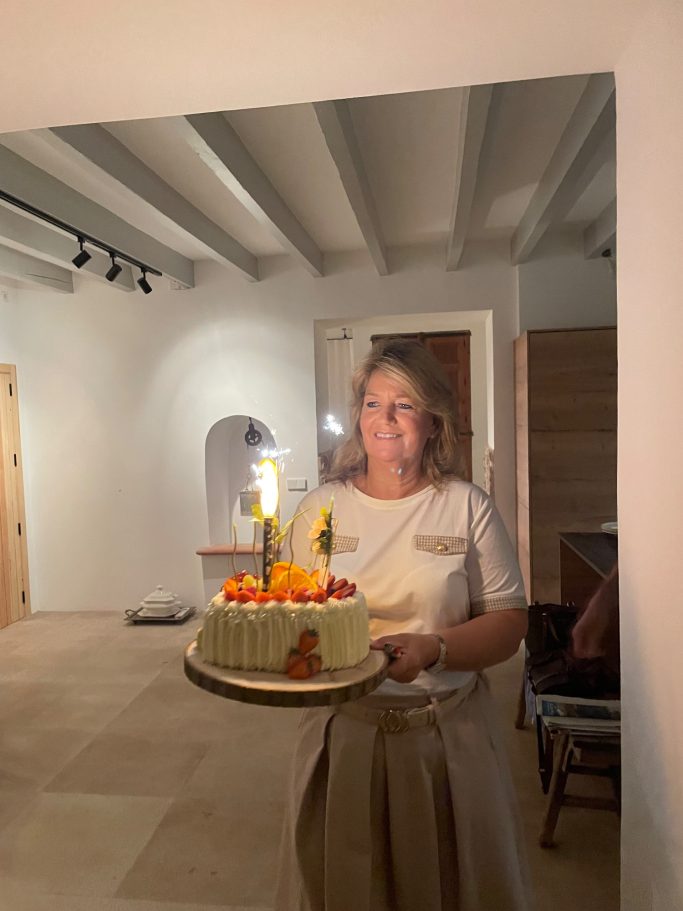 Geburtstagstorte Frau hält eine bunte Geburtstagstorte mit Kerzen in einem hellen Raum.