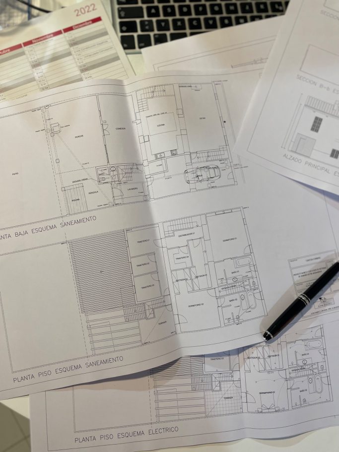 Baubegleitung Baumplan mit mehreren Grundrisszeichnungen und einem Stift auf einem Tisch.